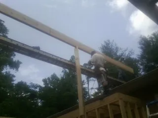 Carpenter setting a ridge beam over a new addition frame — Ice Dam Removal by Roofing Brothers in River Edge