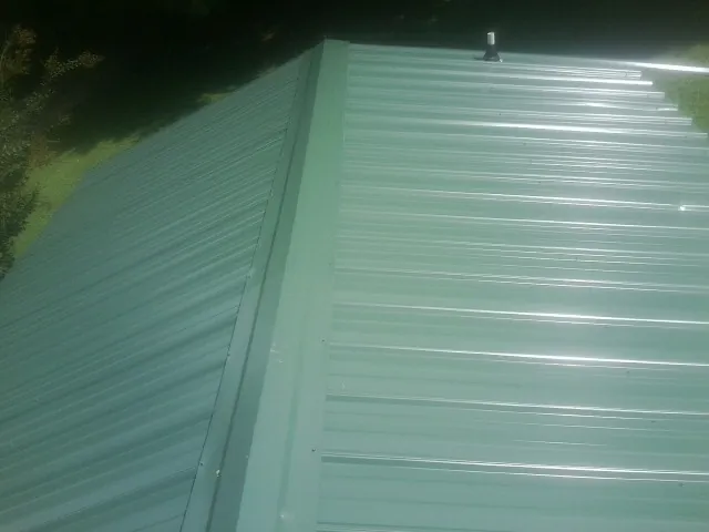 New green metal panels meeting at the ridge of a roof — Flat Roof Repair work by our crew in River Edge
