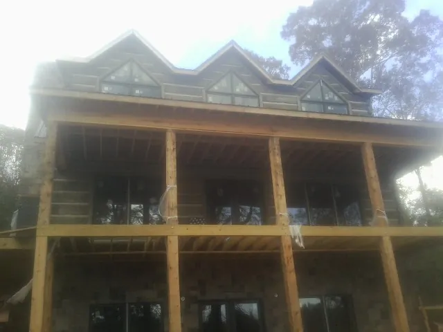Dormers and porch framing on a large log home under construction — Roof Coating work by our crew in River Edge