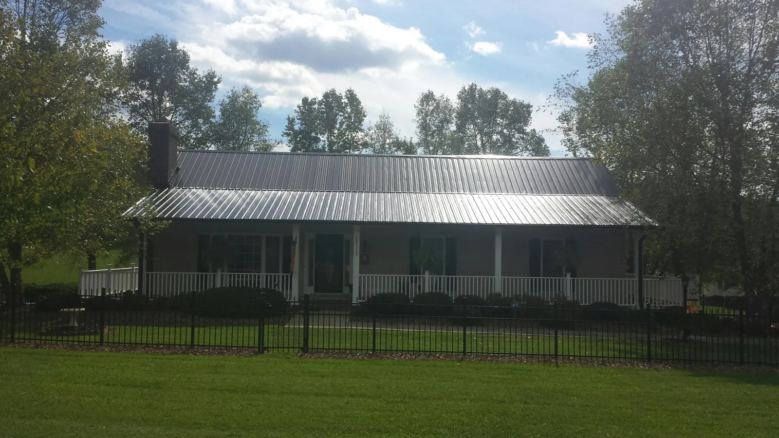 Gray metal roof on a brick ranch with a full width front porch — Gutter Guard Installation work by our crew in River Edge