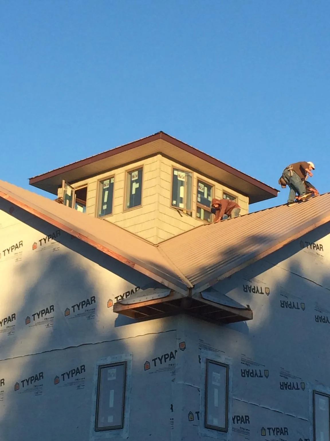 Roofers working around a rooftop cupola on a new metal roof at sunset — Roof Waterproofing in River Edge by Roofing Brothers